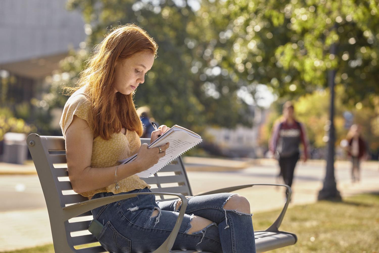 一位<a href='http://uhl.ftigo.com'>bv伟德ios下载</a>学院的学生在校园里的长椅上读书.